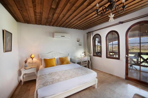 1 dormitorio con 1 cama, 2 mesas y ventanas en VINIFERA VINEYARDS HOTEL, en Selçuk