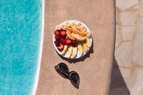 a plate of fruit next to a swimming pool at Carbonaki Hotel in Mikonos