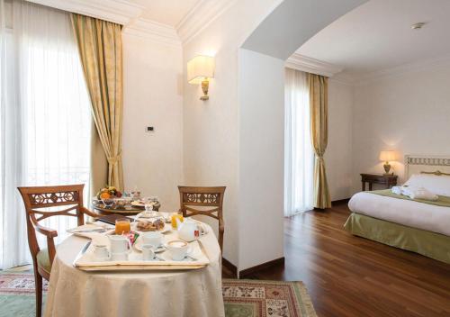 una camera d'albergo con tavolo, sedie e letto di Hotel Fiuggi Terme Resort & Spa a Fiuggi