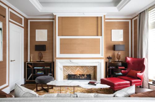 a living room with a fireplace and a red chair at The Cadogan, A Belmond Hotel, London in London