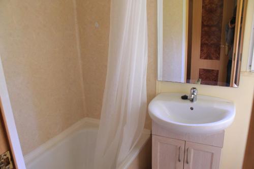 a bathroom with a sink and a tub with a shower curtain at Camping Fragadeume in Monfero