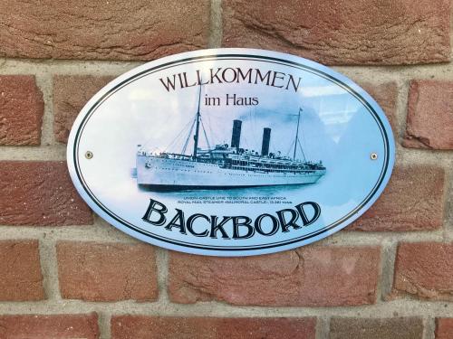 a plaque on a brick wall with a ship on it at "Backbord" by Ferienhaus Strandgut in Born