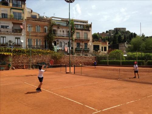 two people playing tennis on a tennis court at Maison Blanche Taormina in Taormina