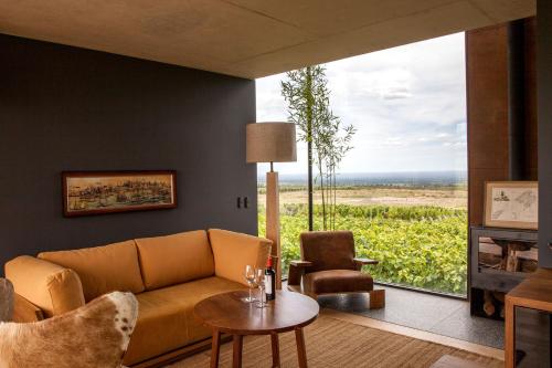 a living room with a couch and a large window at Casa de Uco Vineyards and Wine Resort in Los Árboles