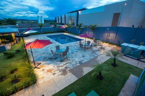 una vista aérea de una piscina con mesas y sombrillas en ibis Styles Parauapebas en Parauapebas