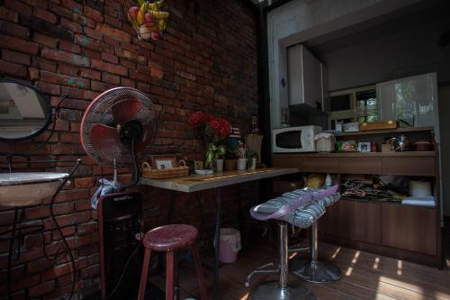 uma cozinha com uma parede de tijolos, uma ventoinha e bancos. em May Rooms Taipei Nangang Station em Taipei
