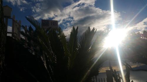 a sun shining in the sky with palm trees at B&B nonnAngela in Maratea