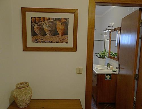 La salle de bains est pourvue d'un lavabo et d'une photo murale. dans l'établissement Casa São João, à Peniche