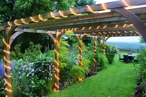 a wooden pergola with lights in a garden at Mallyan Spout Hotel in Goathland