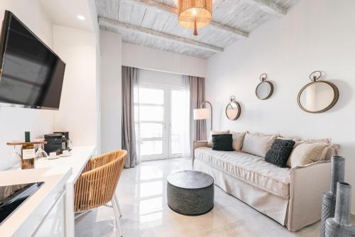a white living room with a couch and a tv at Minthi Boutique Apartments in Hanioti