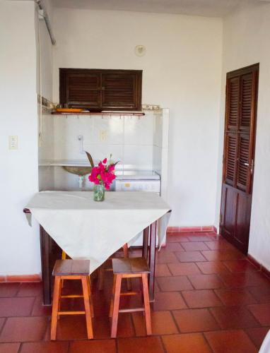 a kitchen with a white table and two stools at Pousada Morada do Sol in Canoa Quebrada