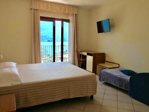 een slaapkamer met een bed en een balkon met een televisie bij Villa Belvedere Hotel in Limone sul Garda