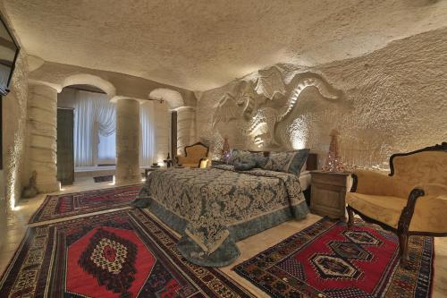 ein großes Schlafzimmer mit einem Bett in einer Steinmauer in der Unterkunft Kayatas Cave Suites in Goreme