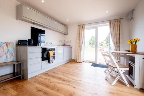 a kitchen with white cabinets and a wooden floor at Maple – Three Tuns Apartments in Pettistree