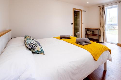 a bedroom with a white bed with a yellow blanket on it at Maple – Three Tuns Apartments in Pettistree