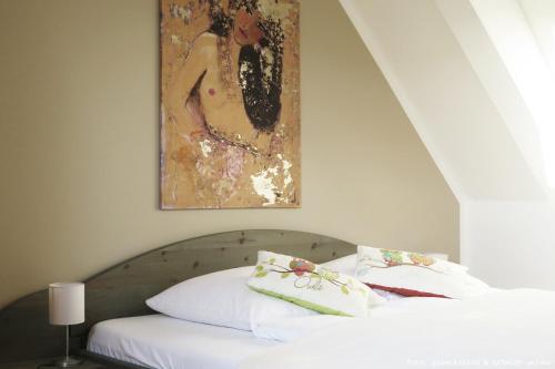 a bed with white sheets and a painting on the wall at Ferienwohnung "Oha" in Bad Berka