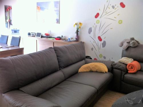 a living room with a brown couch and flowers on the wall at Spacieux Appartement au coin de la plage in Middelkerke