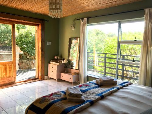 a bedroom with a bed and a large window at Bluebottle Guesthouse in Muizenberg