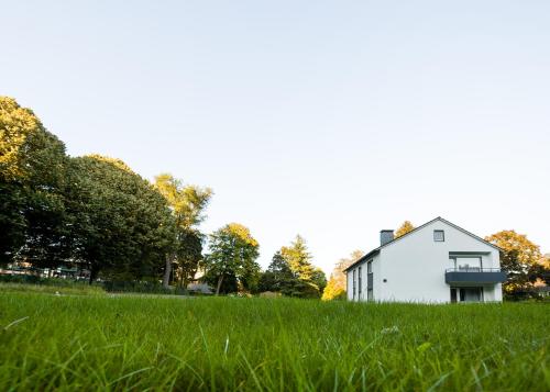 ein weißes Haus auf einem Grasfeld in der Unterkunft Haus am Park - Ihr Gästehaus in Velbert in Velbert