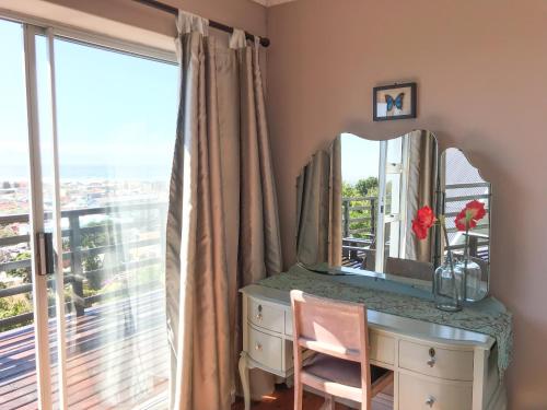 a dressing table with a mirror and a window at Bluebottle Guesthouse in Muizenberg