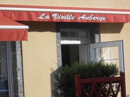 a restaurant with a red awning on a building at La Vieille Auberge in Saint-Privat-dʼAllier