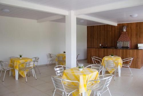 ein Zimmer mit Tischen und Stühlen mit gelbem Tischtuch in der Unterkunft POUSADA DA ILHA in Una