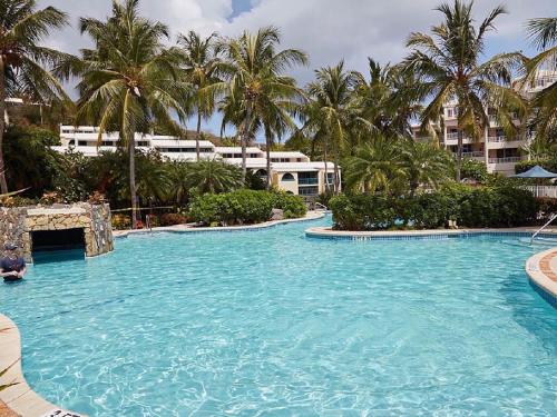 a large swimming pool with palm trees and buildings at Beach Townhouse in St Thomas