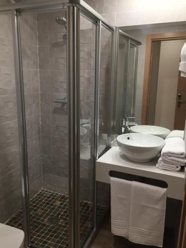 a bathroom with a glass shower and a sink at Hostal Infantes in Toledo
