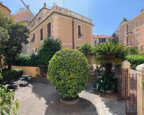 un jardin avec un grand bush devant un bâtiment dans l'établissement Albergo Fiorenza & Banksia Meublè, à Alassio