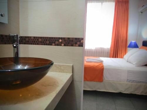 a bathroom with a sink and a bedroom with a bed at Hotel el Atajo in Yopal