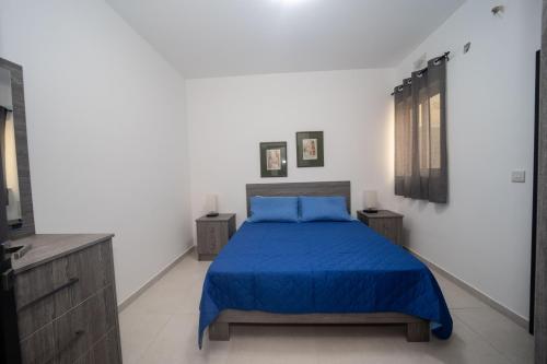 a bedroom with a bed with a blue bedspread at Island Break Residence in Marsalforn