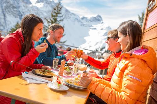 a group of people sitting at a table eating food at Appartement Ideal by A-Appartments in Bürserberg