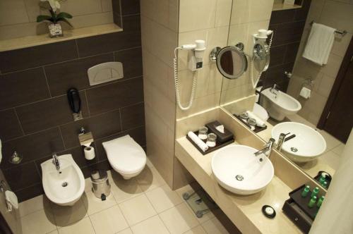 a bathroom with two sinks and a toilet and a mirror at Ramada Downtown Abu Dhabi in Abu Dhabi