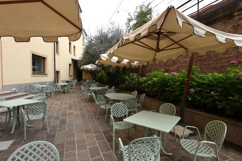 an outdoor patio with tables and chairs and umbrellas at Hotel Acqui & Centro Benessere in Acqui Terme