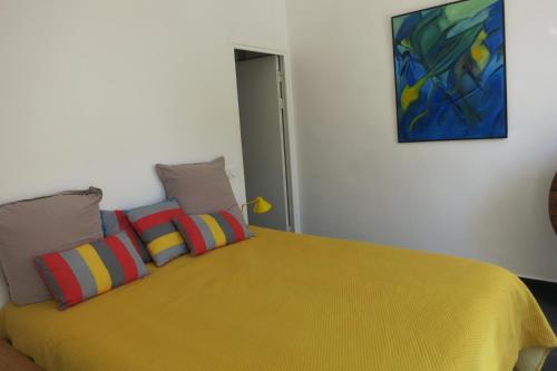 Villa les Lys في لا سين سور مير: غرفة نوم مع سرير أصفر مع وسائد ملونة