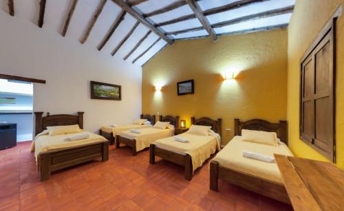 a room with four beds in a room at Hotel Hacienda Santa Barbara in San Gil