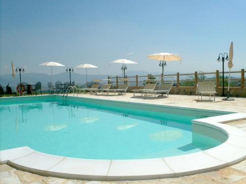 a large blue swimming pool with chairs and umbrellas at Poggio Desto Bed & Breakfast in Quarrata