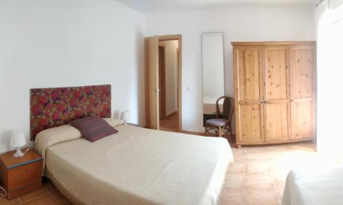 a bedroom with a large bed and a wooden cabinet at Apartamento Pescadors in Les Cases d'Alcanar