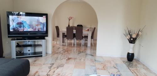 a living room with a television and a table with chairs at Casa da Lagoa in Calheta