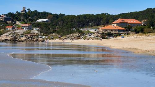 a beach with a group of people walking on the sand at Hotel Samar in A Lanzada