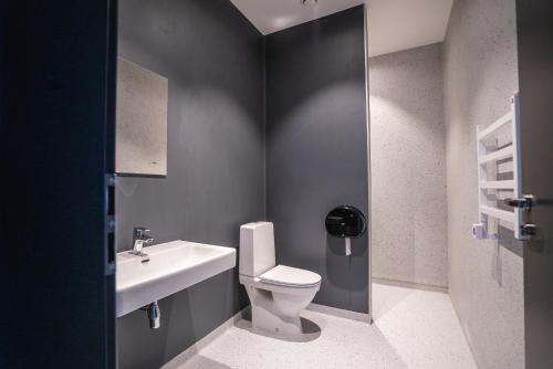 La salle de bains est pourvue de toilettes blanches et d'un lavabo. dans l'établissement Light House Coliving, à Klaipėda