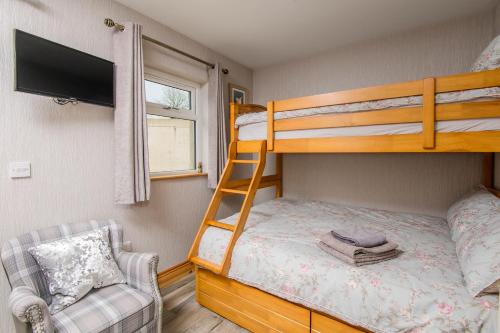a bedroom with a bunk bed with a tv and a chair at Annslea in Lisburn