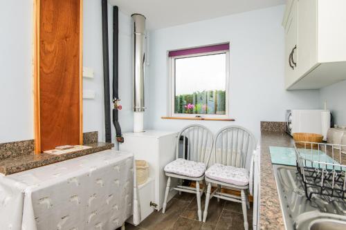 a kitchen with two chairs and a glass table at Annslea in Lisburn