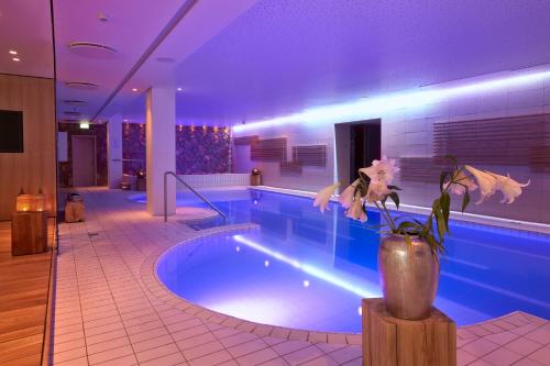 a swimming pool in a hotel with a vase with a plant at Reykjavik Natura - Berjaya Iceland Hotels in Reykjavík