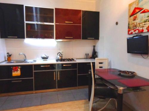 a kitchen with black cabinets and a small table at Guest House, Old-Si in Tbilisi City