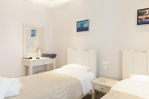 a white bedroom with two beds and a sink at Villa Adriana Hotel in Agios Prokopios