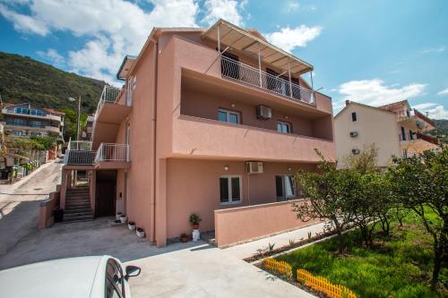 a pink house with a hill in the background at Libra Apartments in Tivat