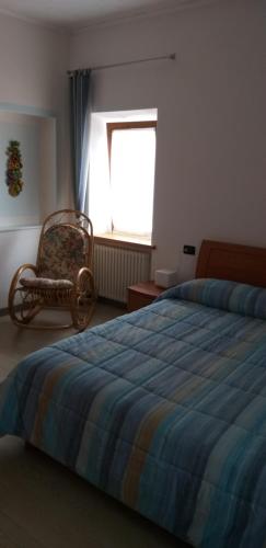 1 dormitorio con 1 cama, 1 silla y 1 ventana en Casa Sonia, en Auronzo di Cadore