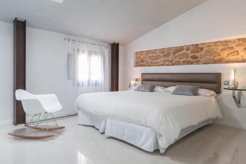 a white bedroom with a large bed and a chair at Can Vent Boutique Hotel in Alcudia