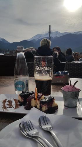 a table with a plate of food and a glass of beer at Koko's apartments in Bansko